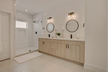 Primary bathroom with light wood double vanity and walk-in shower
