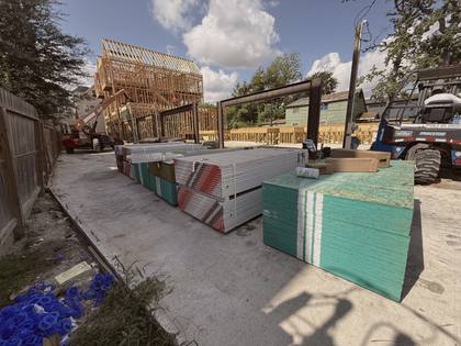 Wood framing in progress with steel beams and staged building materials at Residences on 24th